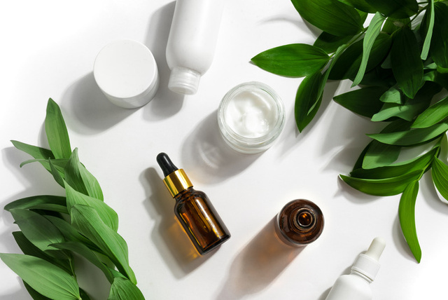 Skincare bottles arranged with green leaves