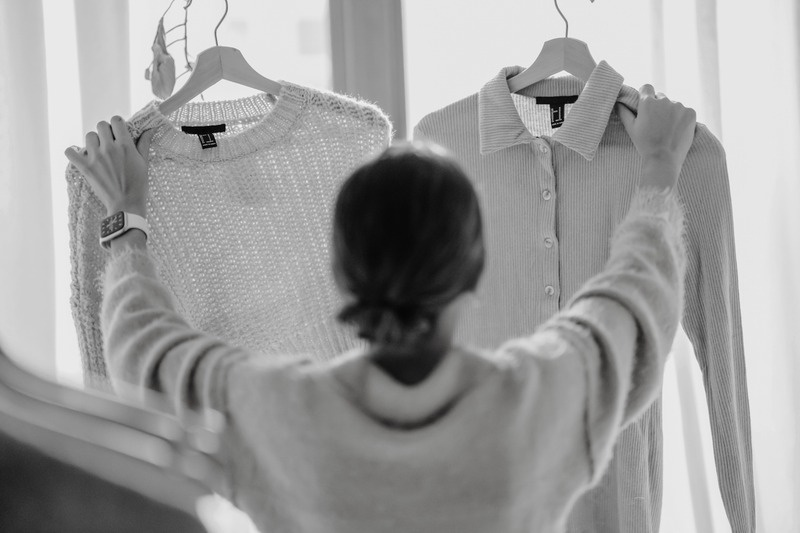 Person choosing between two shirts on hangers