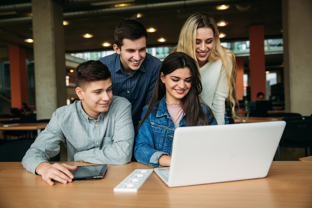 Group of students gathered around a laptop
