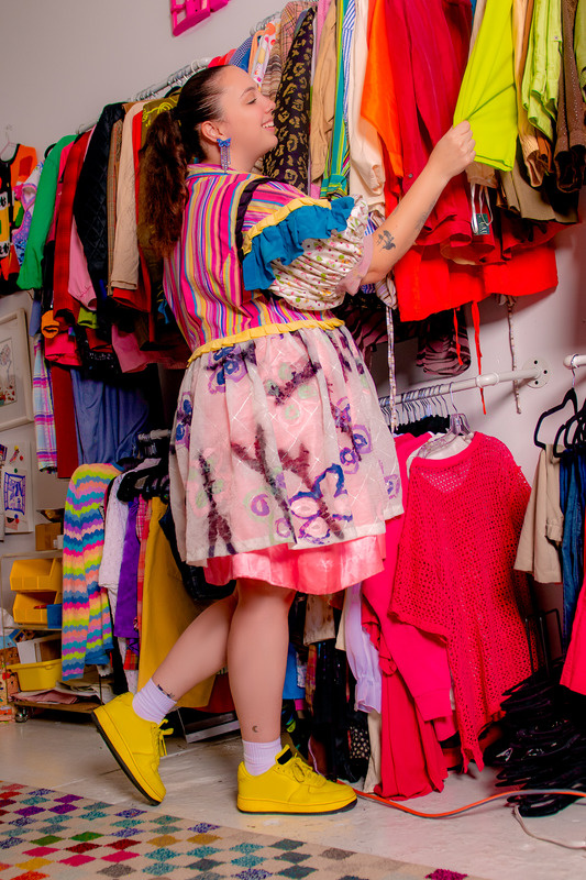 Young shopper pulling pieces from a bright thrift rail